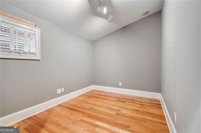 spare room featuring lofted ceiling and hardwood / wood-style floors