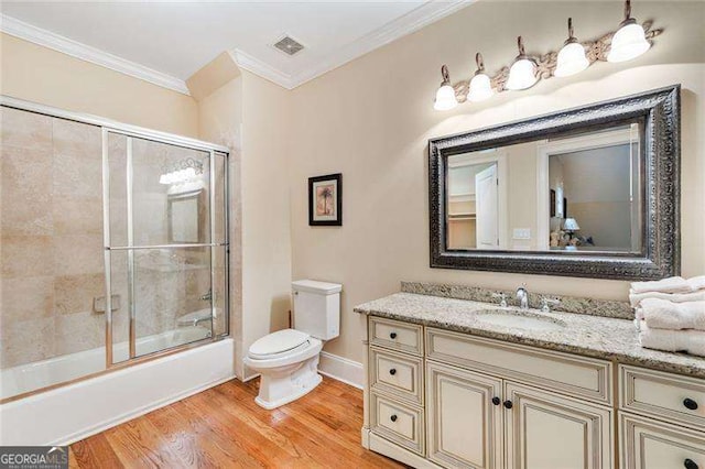 full bathroom with wood-type flooring, vanity, combined bath / shower with glass door, crown molding, and toilet