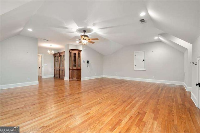 additional living space with lofted ceiling, electric panel, a chandelier, and light hardwood / wood-style flooring