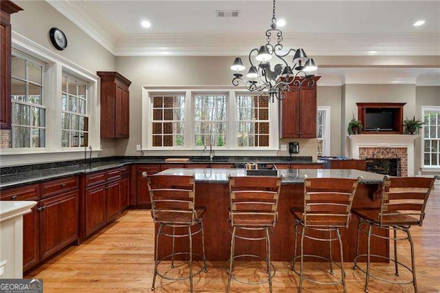 3201 Hobsons Ridge Trl NW, Acworth, GA 30101 - kitchen with light wood-style floors, a fireplace, a kitchen island, healthy amount of natural light, and crown molding