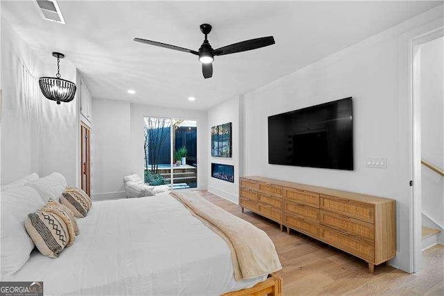 bedroom featuring access to exterior, light hardwood / wood-style floors, and ceiling fan with notable chandelier