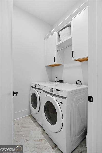 washroom featuring washer and clothes dryer and cabinets