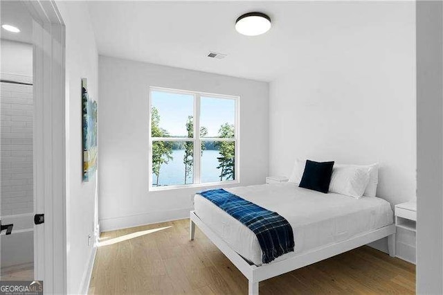 bedroom with a water view and wood-type flooring