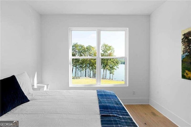 bedroom with a water view and wood-type flooring