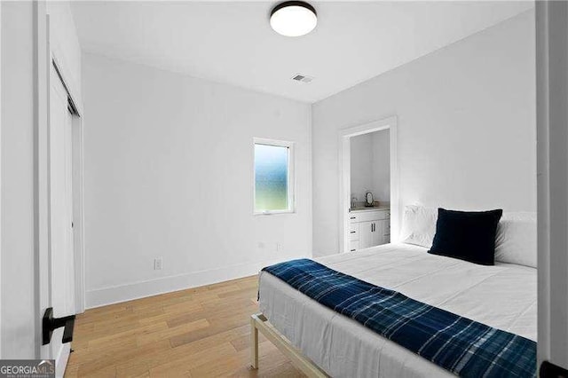 bedroom with light hardwood / wood-style floors and ensuite bathroom