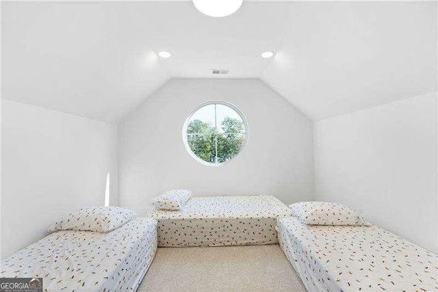 bedroom with vaulted ceiling and light colored carpet