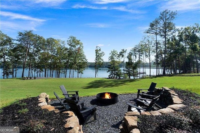 view of property's community featuring an outdoor fire pit, a water view, and a lawn