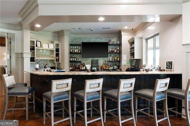 bar with dark hardwood / wood-style floors, white cabinets, ornamental molding, and tasteful backsplash