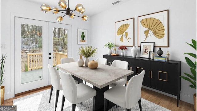 dining space featuring an inviting chandelier, visible vents, wood finished floors, and french doors