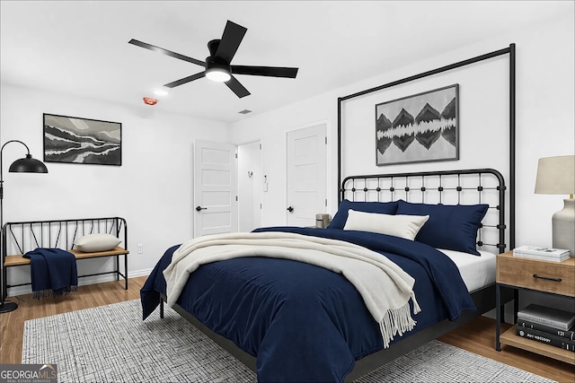 bedroom with ceiling fan, wood finished floors, and baseboards