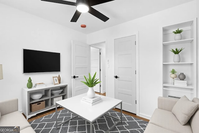 living room with a ceiling fan, built in features, and dark wood-style flooring