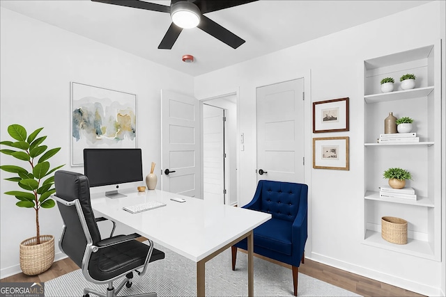 office with a ceiling fan, baseboards, built in features, and wood finished floors