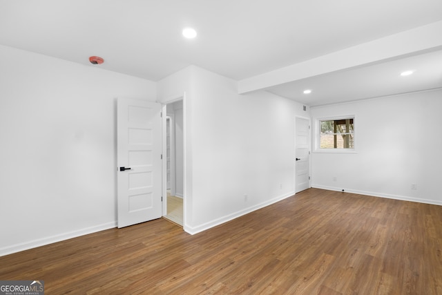 empty room featuring baseboards, beamed ceiling, wood finished floors, and recessed lighting