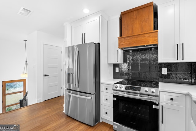 kitchen with visible vents, appliances with stainless steel finishes, light wood-style floors, white cabinetry, and premium range hood