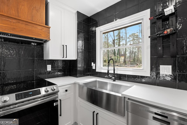 kitchen featuring tasteful backsplash, dishwashing machine, custom range hood, stainless steel range with electric cooktop, and a sink