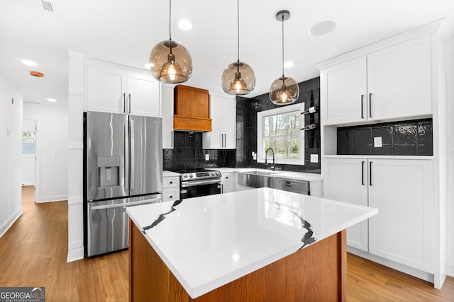 kitchen with light wood-style flooring, decorative backsplash, appliances with stainless steel finishes, white cabinetry, and a sink