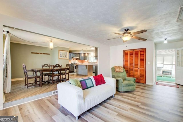 living room with light hardwood / wood-style flooring, ceiling fan, and a textured ceiling