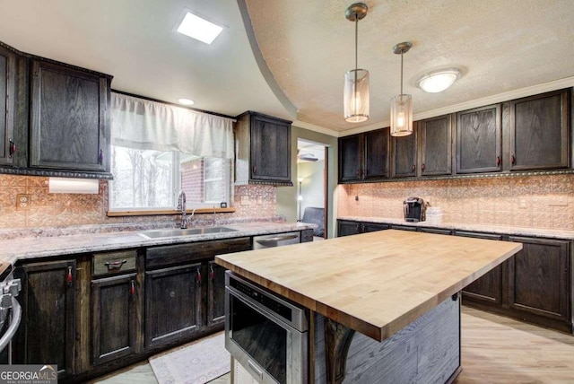 kitchen with a kitchen island, sink, dark brown cabinetry, and wooden counters