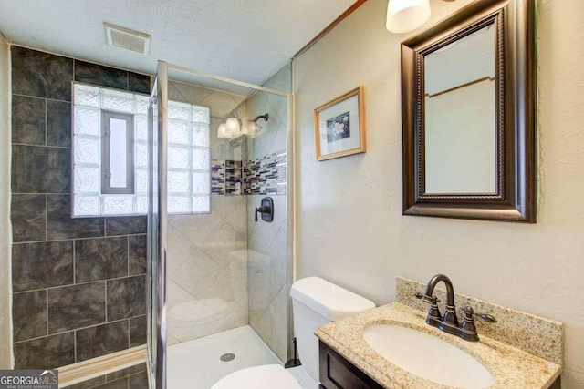 bathroom featuring an enclosed shower, vanity, toilet, and a textured ceiling