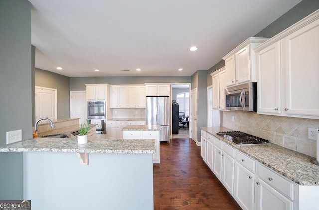 kitchen featuring white cabinets, stainless steel appliances, light stone countertops, and kitchen peninsula