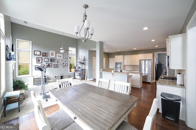 dining room with ceiling fan with notable chandelier, dark hardwood / wood-style floors, and a healthy amount of sunlight