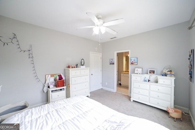 bedroom with ceiling fan, ensuite bath, and light colored carpet