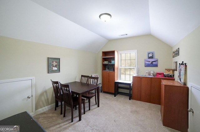 carpeted dining room with vaulted ceiling