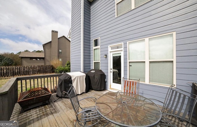 wooden deck featuring an outdoor fire pit and a grill