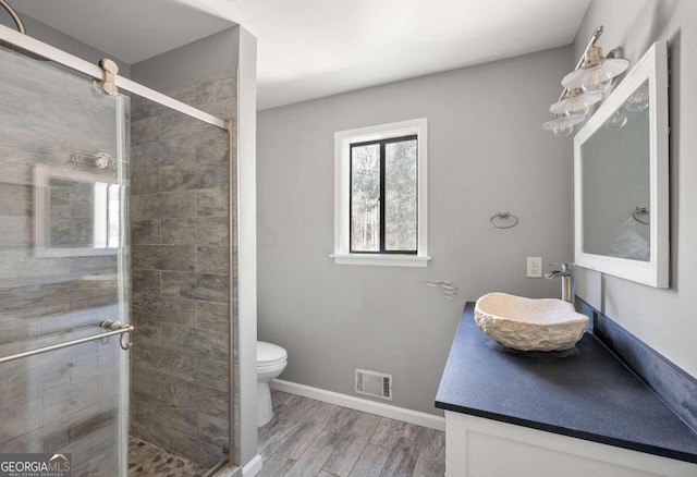 bathroom featuring toilet, vanity, walk in shower, and wood-type flooring