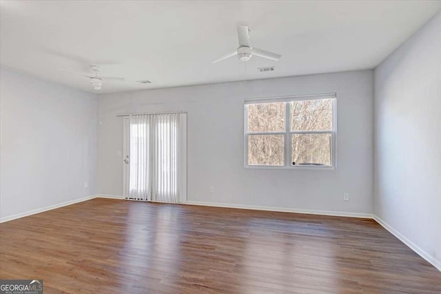 spare room with a wealth of natural light, ceiling fan, and dark hardwood / wood-style flooring