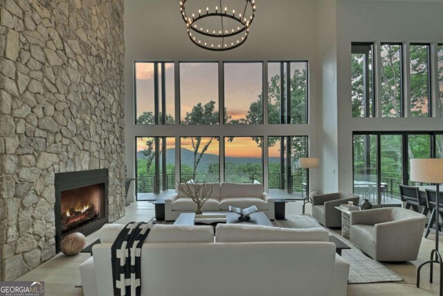 415 Green Ridge Trl, Blue Ridge, GA 30513 - living room with light wood-type flooring, a towering ceiling, an inviting chandelier, and a stone fireplace