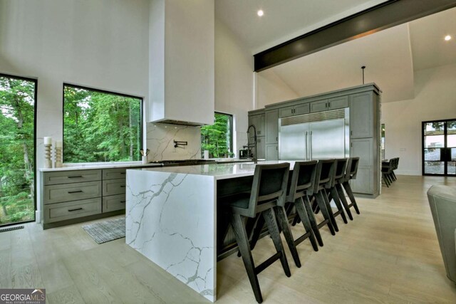415 Green Ridge Trl, Blue Ridge, GA 30513 - kitchen with light wood-type flooring, a kitchen breakfast bar, stainless steel built in refrigerator, high vaulted ceiling, and decorative backsplash