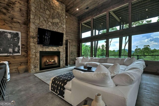 415 Green Ridge Trl, Blue Ridge, GA 30513 - living room featuring a stone fireplace, concrete flooring, a towering ceiling, wood ceiling, and wood walls