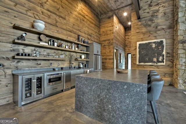 415 Green Ridge Trl, Blue Ridge, GA 30513 - bar with high vaulted ceiling, wood walls, gray cabinets, sink, and wine cooler