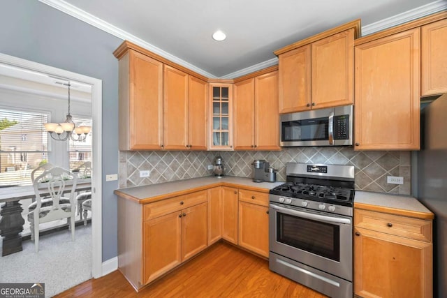 kitchen featuring light hardwood / wood-style floors, stainless steel appliances, backsplash, and ornamental molding