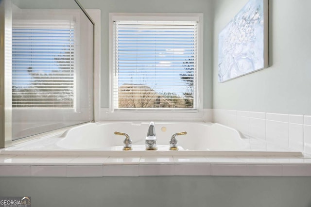 bathroom with tiled tub and a wealth of natural light