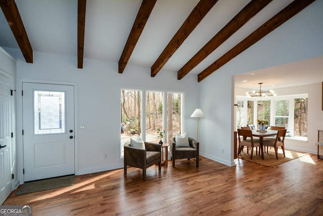 foyer entrance with plenty of natural light, a notable chandelier, vaulted ceiling with beams, and wood finished floors