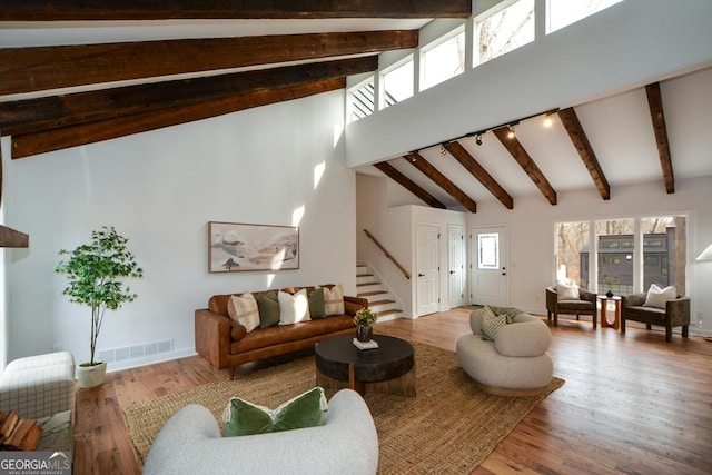 living room featuring high vaulted ceiling, stairway, wood finished floors, and a healthy amount of sunlight