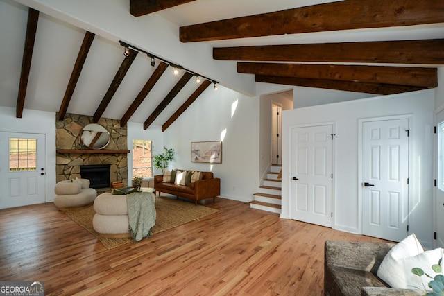 living area featuring plenty of natural light, a fireplace, stairway, and light wood-style flooring