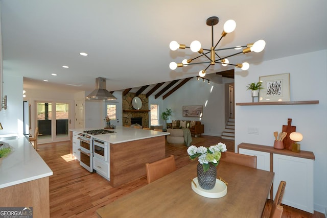 dining space featuring a stone fireplace, recessed lighting, light wood-style floors, vaulted ceiling, and stairway