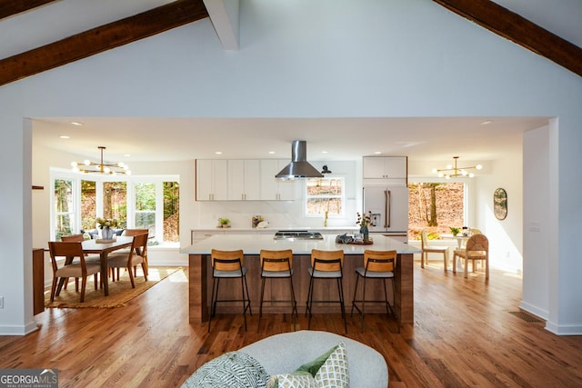 kitchen featuring white cabinets, island exhaust hood, stainless steel appliances, light countertops, and a chandelier