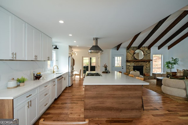 kitchen featuring stainless steel appliances, a sink, white cabinets, open floor plan, and light countertops