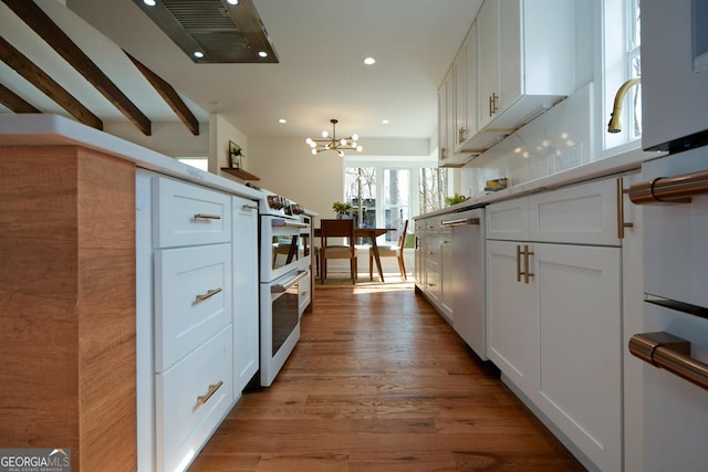 kitchen featuring white cabinets, dishwasher, wood finished floors, a chandelier, and recessed lighting