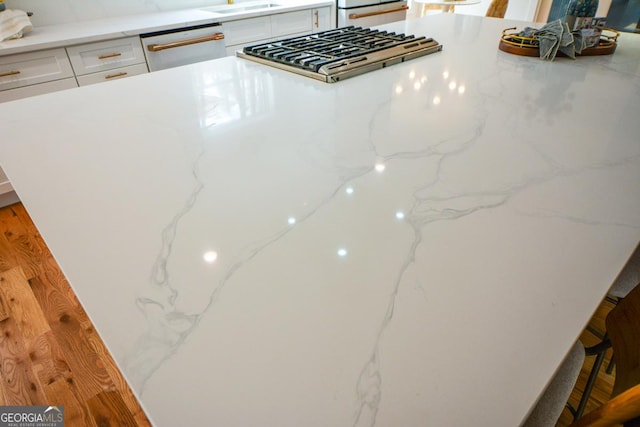 kitchen featuring appliances with stainless steel finishes, a kitchen bar, light stone countertops, and white cabinets