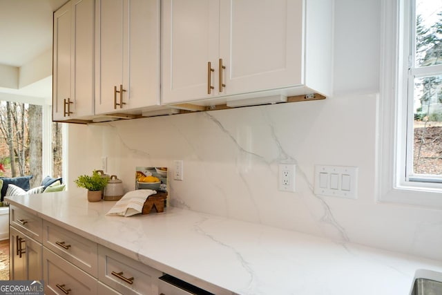 kitchen featuring tasteful backsplash, white cabinets, and light stone countertops