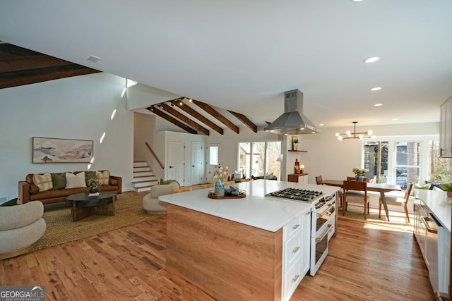 kitchen with vaulted ceiling with beams, white cabinetry, a kitchen island, island range hood, and double oven range