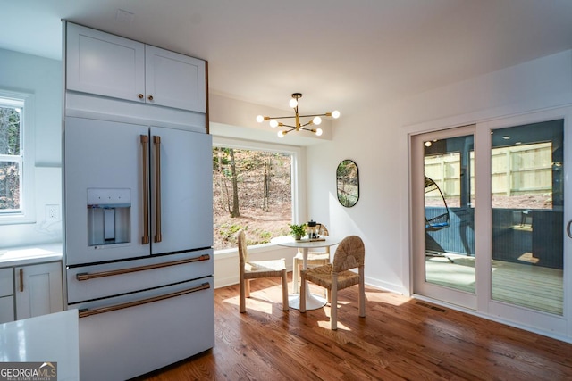 dining space featuring a healthy amount of sunlight, visible vents, a chandelier, and wood finished floors