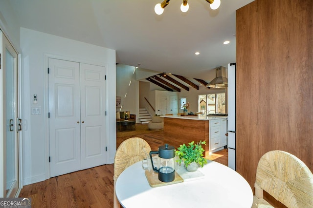 dining space with lofted ceiling with beams, light wood-type flooring, stairway, and recessed lighting