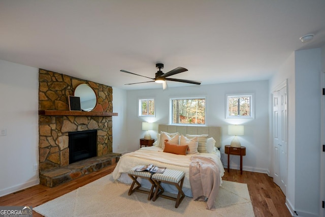 bedroom featuring multiple windows, a fireplace, and wood finished floors