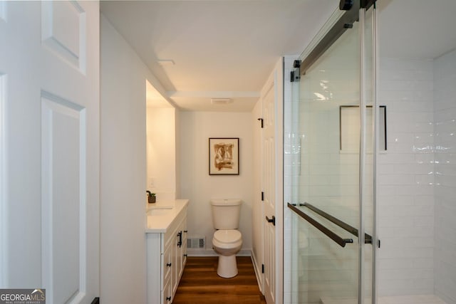 full bathroom featuring a stall shower, visible vents, toilet, wood finished floors, and vanity